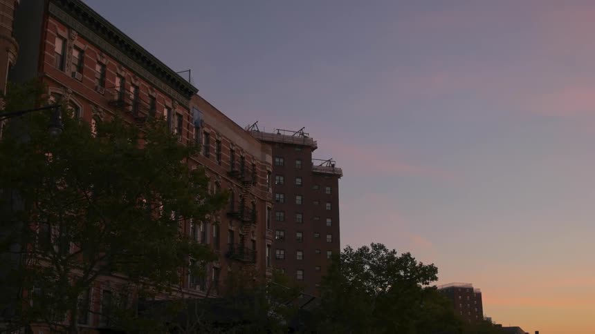 Apartment building with trees in front of it at sunset