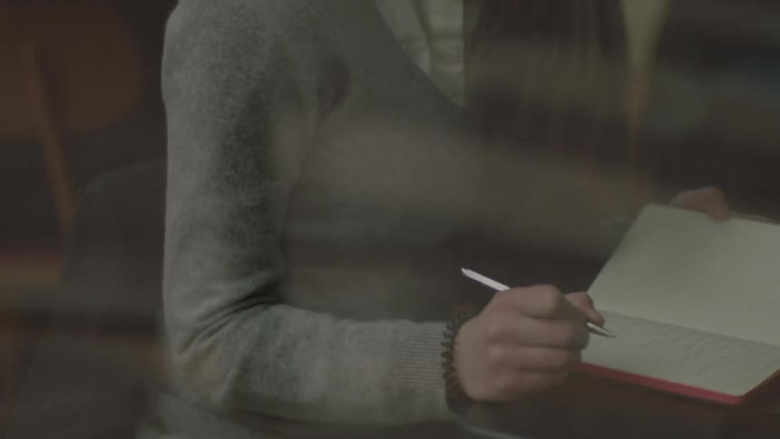 A woman is writing in a small notebook