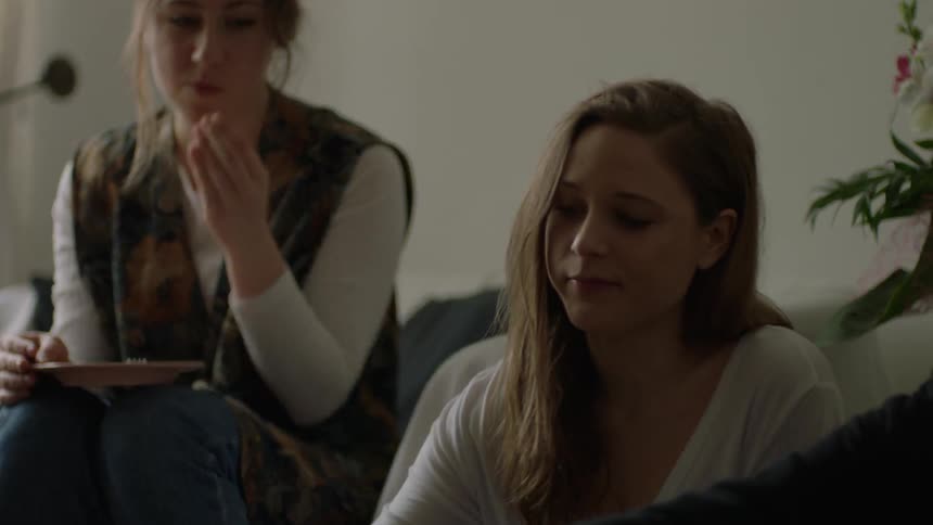 Women gather around a coffee table and eat food