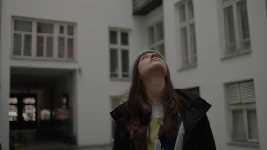 A woman looks around in a building courtyard