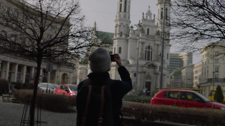 Person takes a picture of a large building in the middle of a city