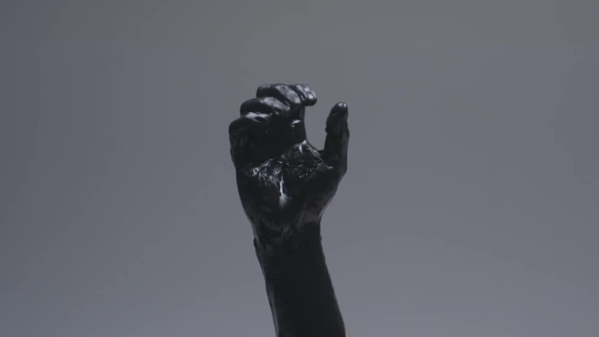 A dark fist slowly opens and spreads it's fingers wide