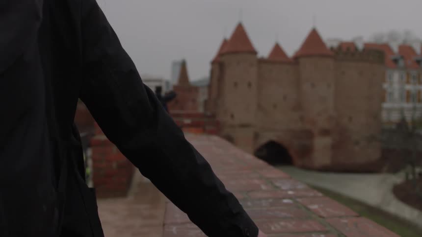A woman walks along a building ledge