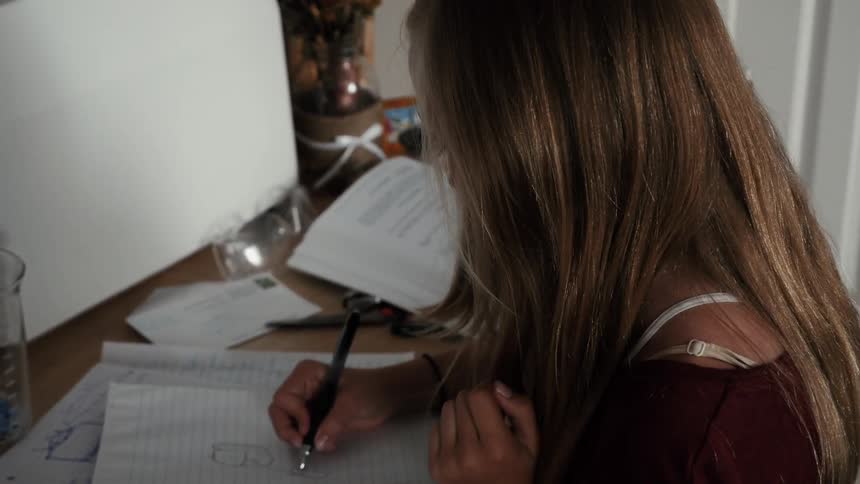 Young woman draws in a notebook with a pen