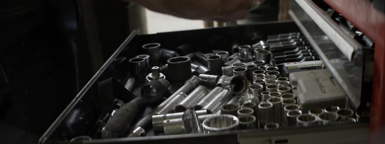 A mechanic goes through tools in a chest