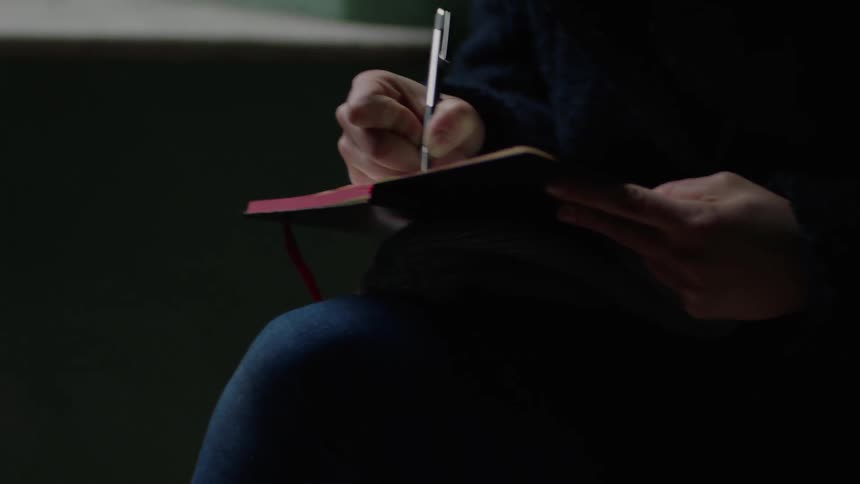 Person sits and writes in a small book
