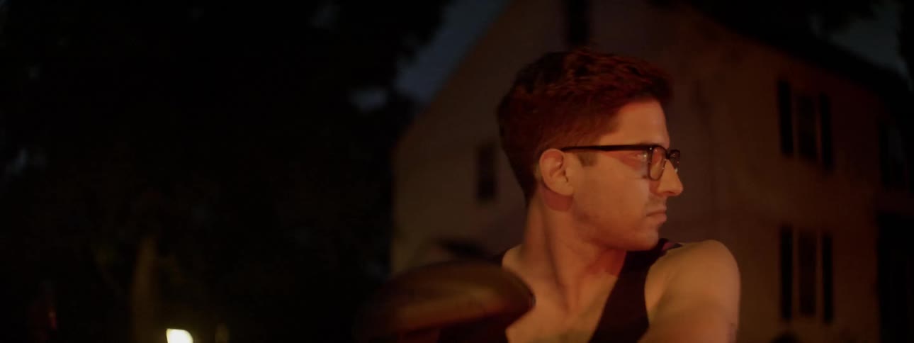 Man sits outside at night illuminated by yellow light