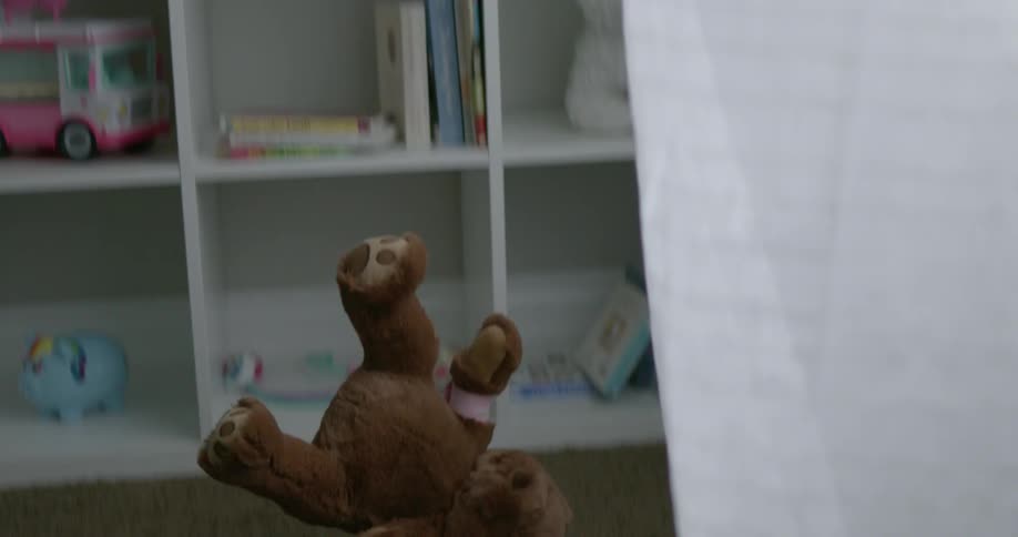A stuffed bear falls to the ground in a child's room