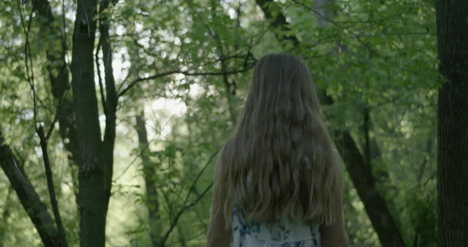 Girl with long hair walks through the woods