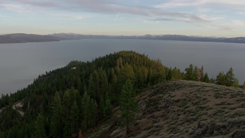 Pine trees surround mountain lake at sunset