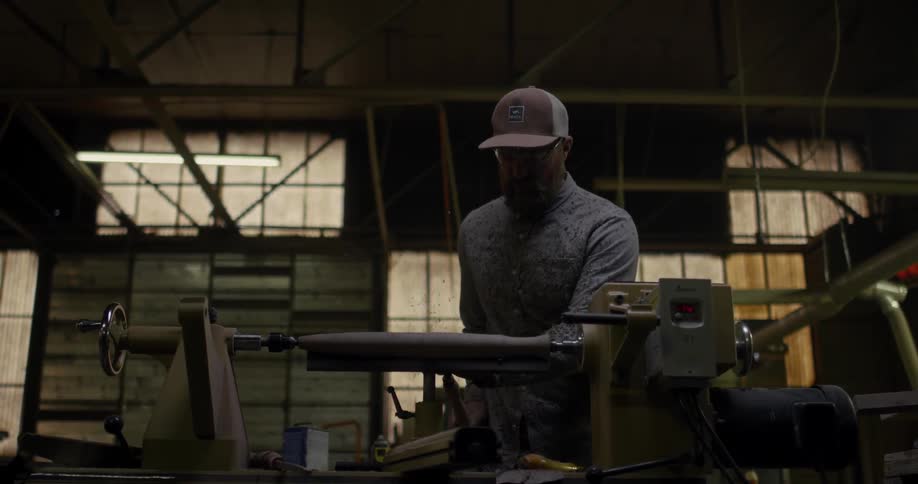 A wood worker works on a piece of wood spinning on a lathe