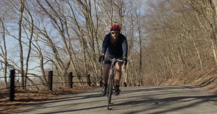 Man pedals a bike quickly down a tree lined trail
