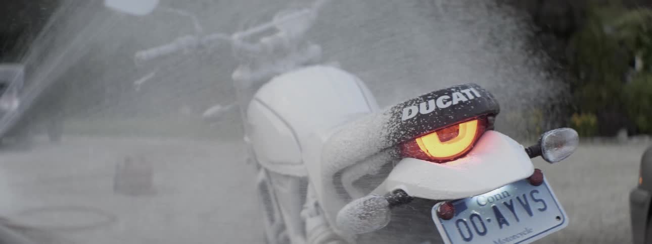 A motorcycle is sprayed with foamy soap