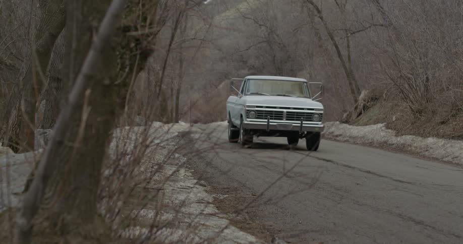 Two men ride in a truck on a mountain road
