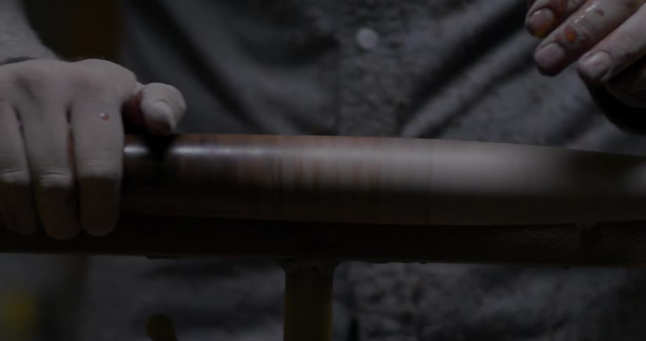A man rubs a finish on a spinning piece of wood