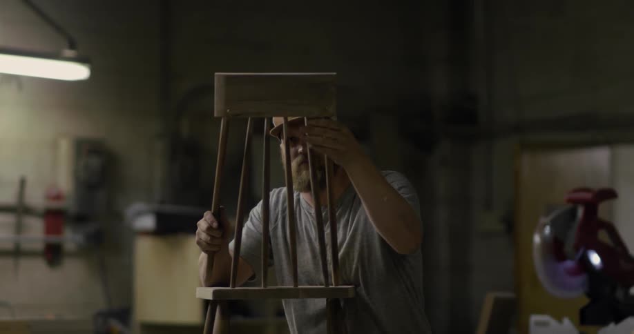 A wood worker assembles a small chair in a workshop