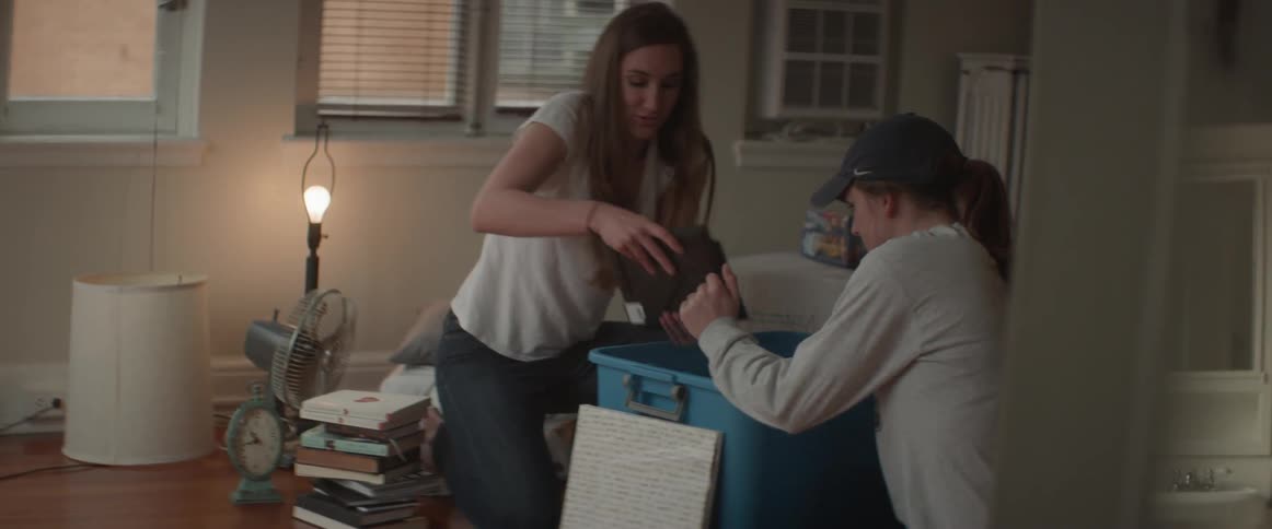 Two women remove books from a container