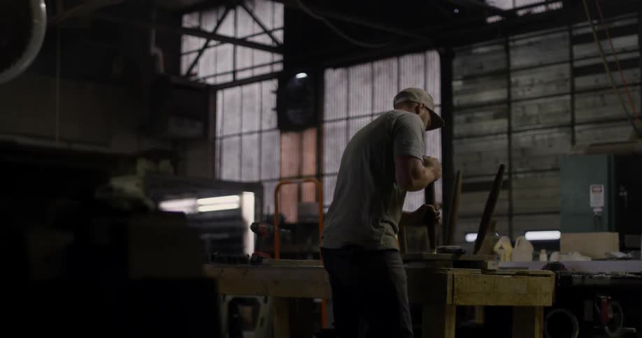 Man hammers then twists a leg on a stool