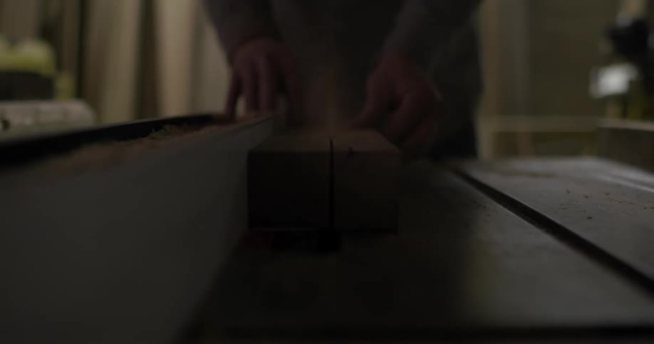 A wood worker cuts a piece of lumber