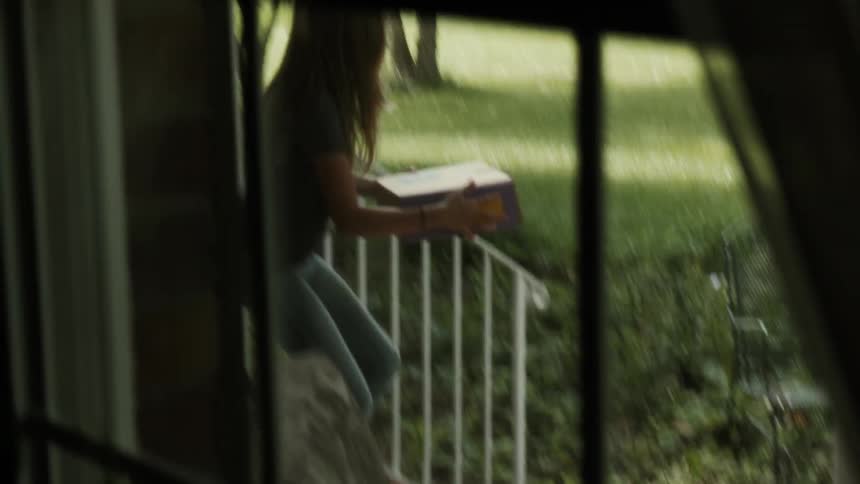 A girl picks up a box and runs in the house