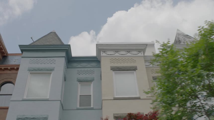 Trees line a street with row houses and brown stones