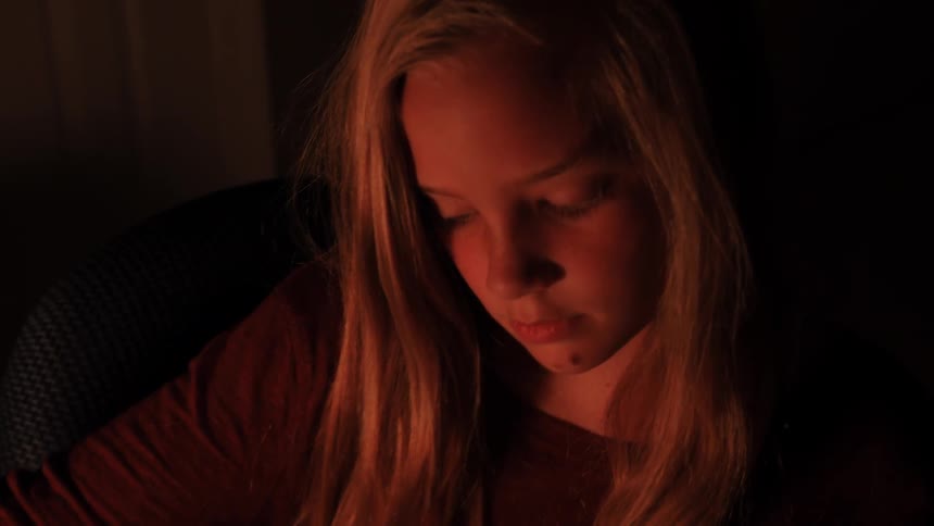 A girl is working on something in a dark room