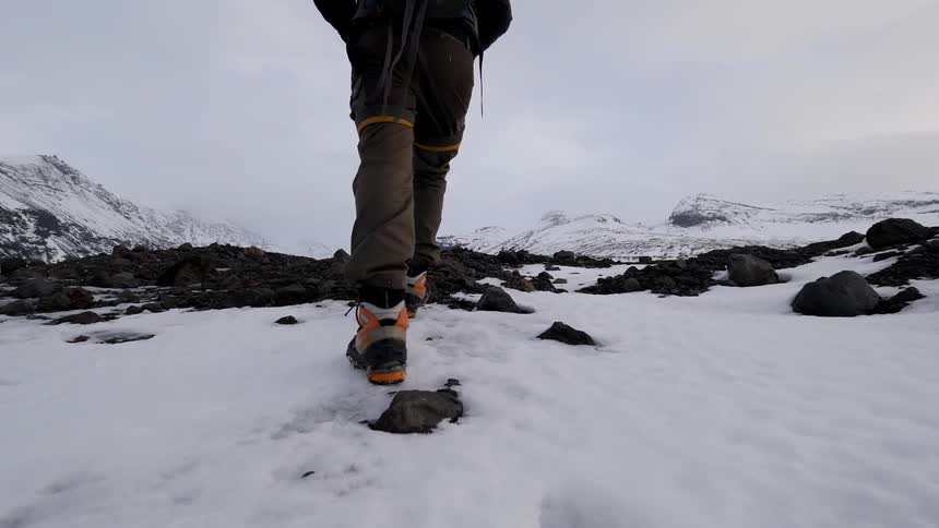 Person wearing a backpack hikes over snowy landscape