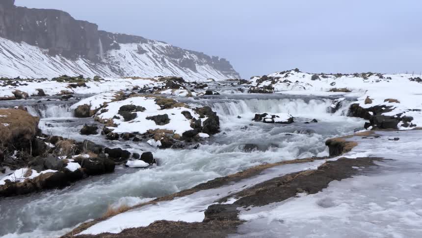 A river flows over rocks in the snow covered landscape
