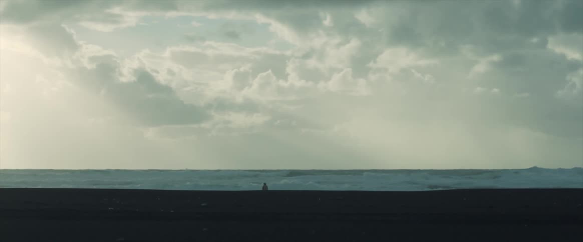 A person stands on the sand as waves crash onshore