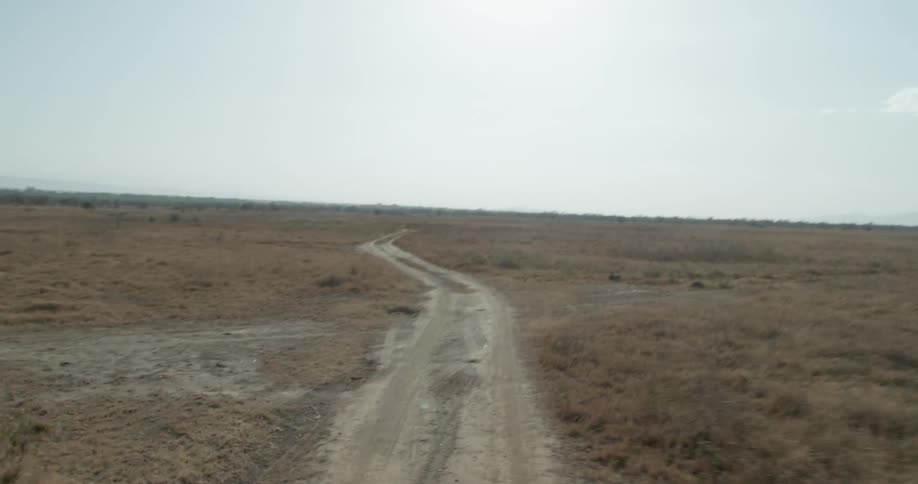A vehicle drives on a rural dirt road