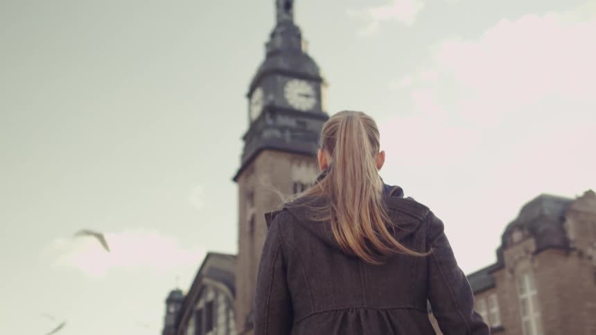 A woman walks towards a clock tower