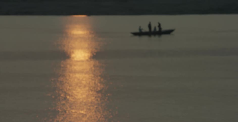 A group of people travel in a row boat at sunset