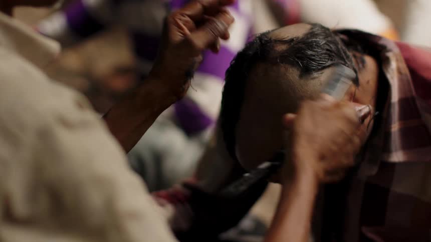 Person shaves the hair off a man's head with a single blade