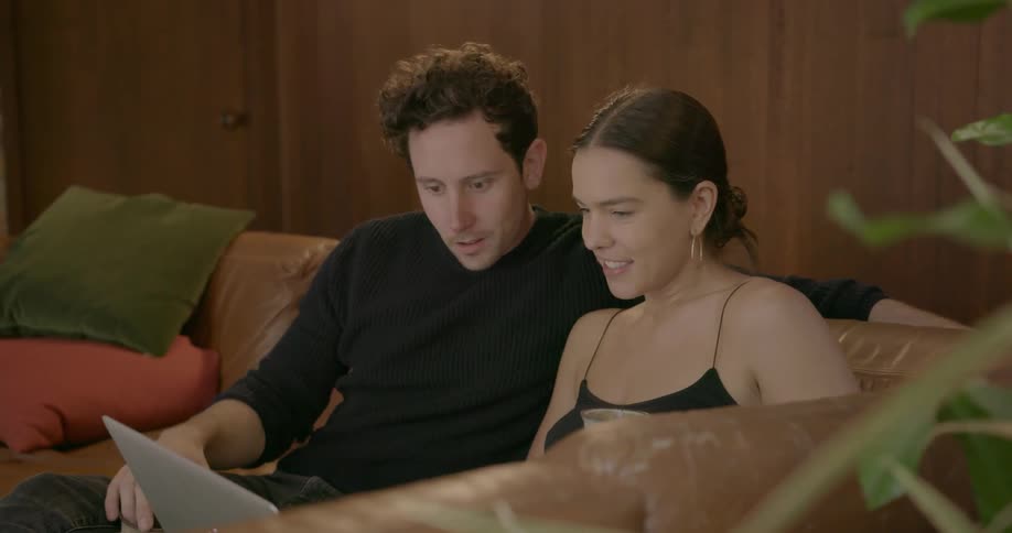A man and woman sit and look at a laptop