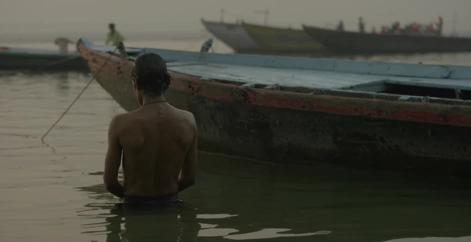 A man stands in the water near a boat