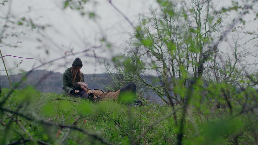 Two people rest on a hillside