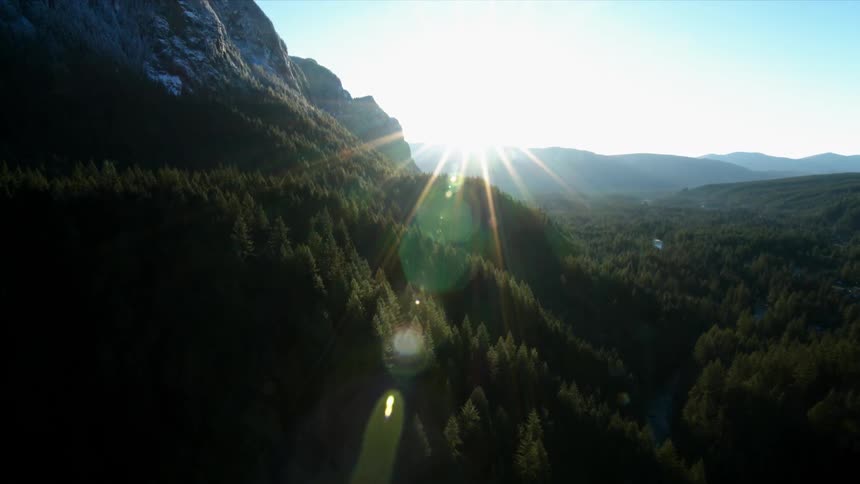 The sun rises over a forested mountain