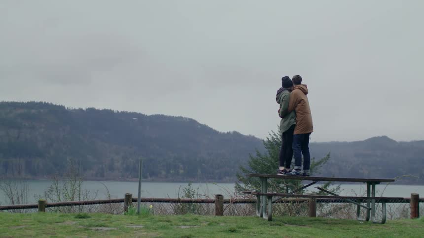 Couple stand hugging on a picnic table