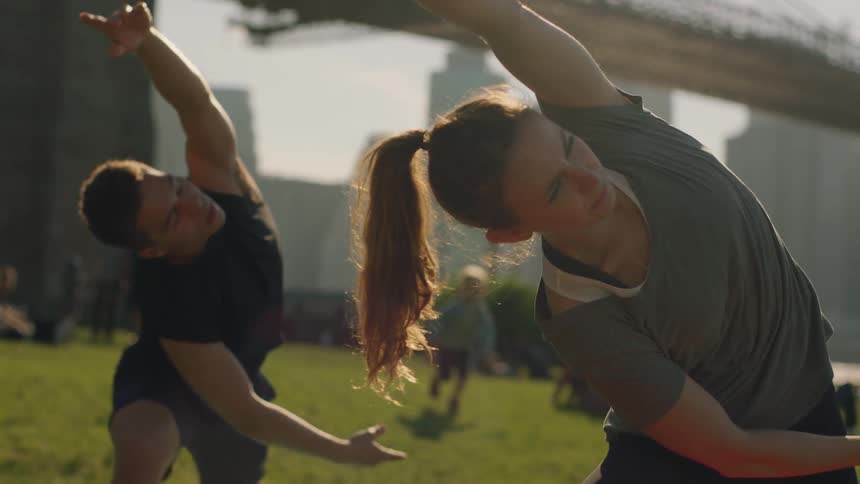 A man and woman stretch on the grass on a sunny day