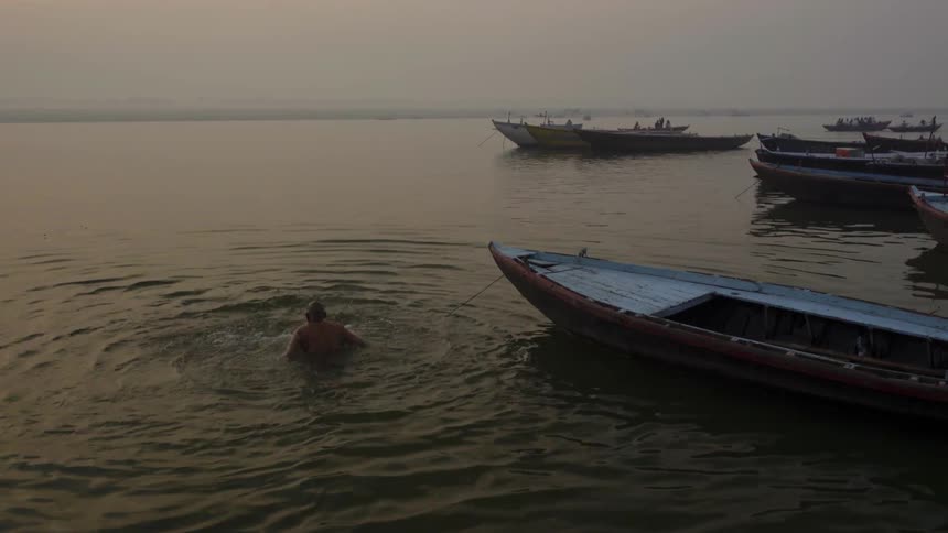 Man jumping up and down in the water next to a boat
