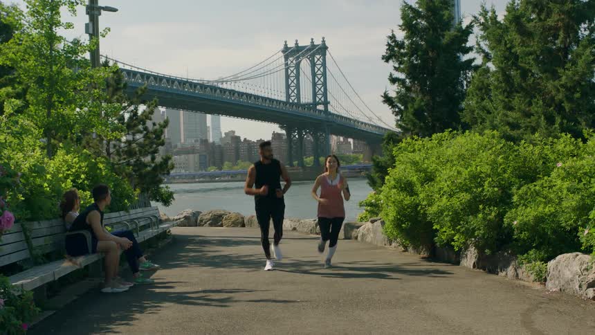 A man and woman jog down a trail