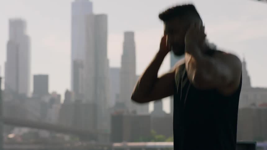 A jogger puts ear buds in his ears and starts running in a city