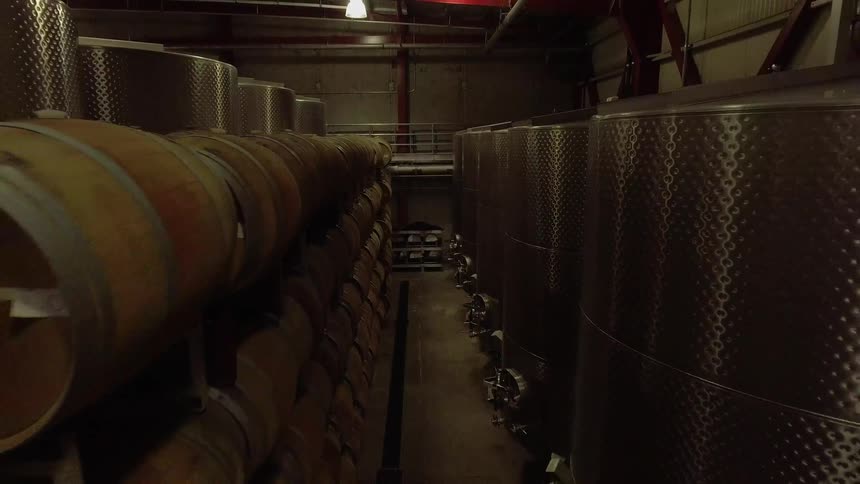 Barrels stacked and lined up next to large metal drums