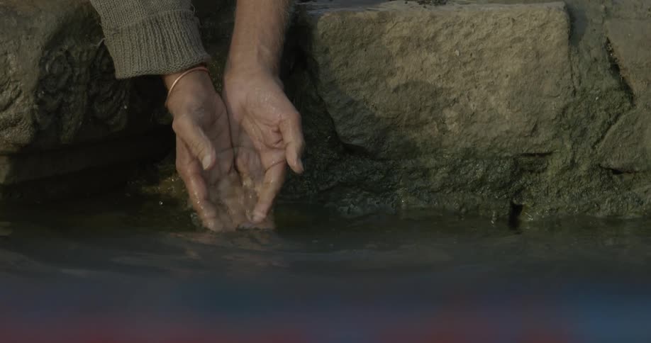 A man splashes his hands in a river