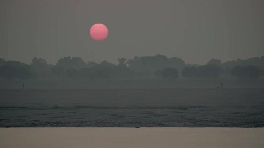 The sun glows as it rises over a river