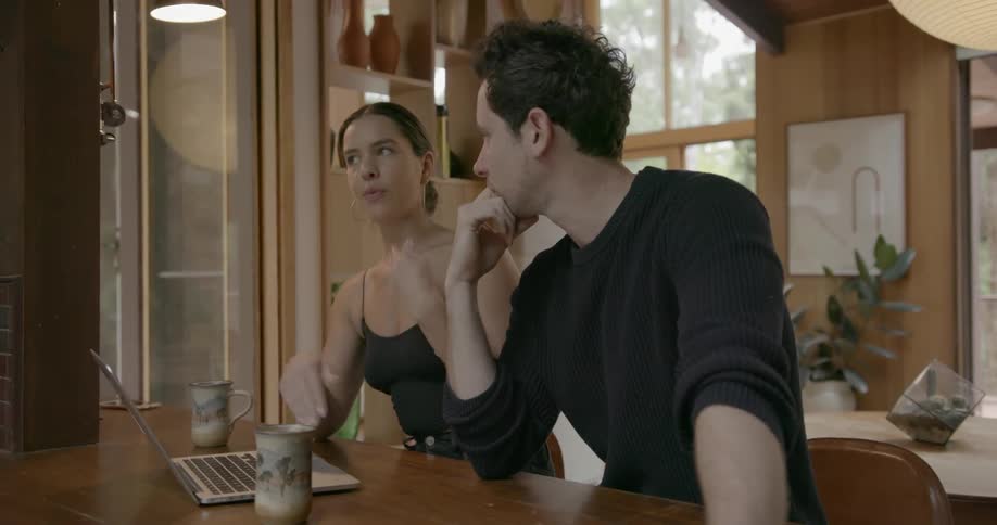 A man and woman sit at a table with a laptop