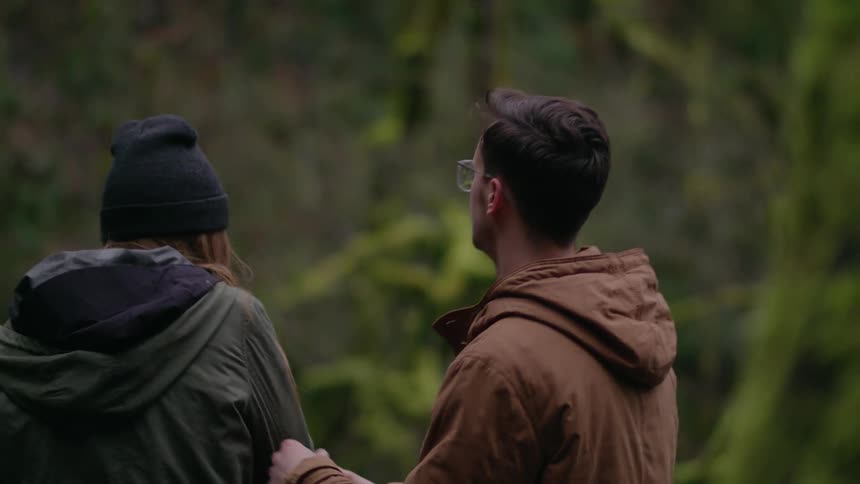 A man and woman kiss in the forest