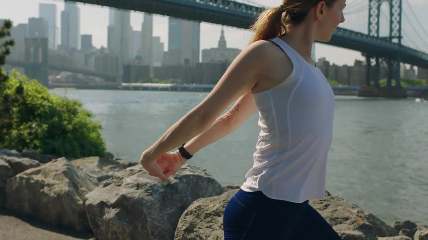 A woman stretches by the bridge