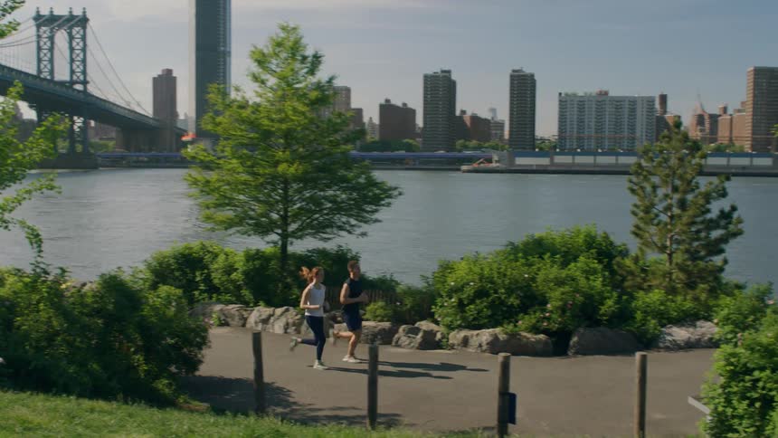 Two joggers run alongside the water