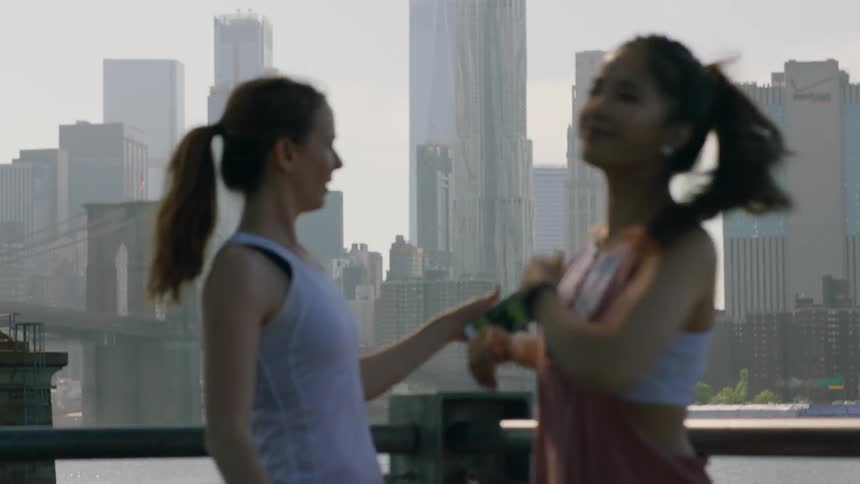 Two women stretch before a city